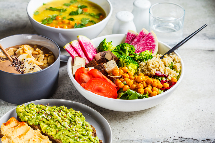 bright and colorful vegan food in bowls on white countertop 